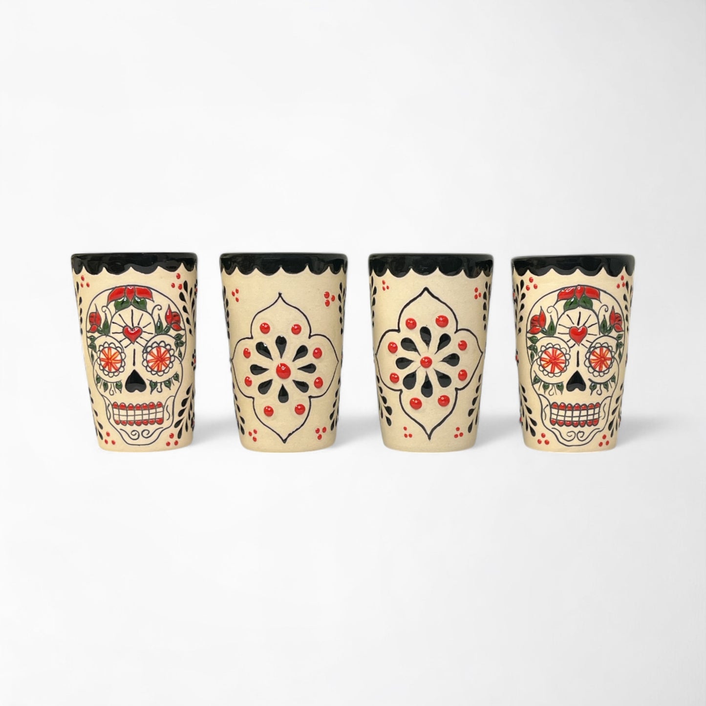 Four decorative ceramic shot glasses with detailed hand painted Day of the Dead sugar skulls